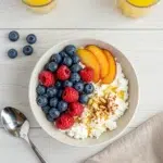 Cottage cheese and fruit breakfast bowl with berries, peach slices, and honey