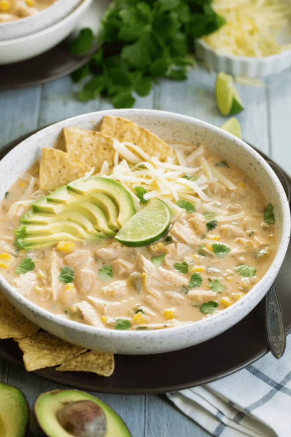 Serving white chicken chili with toppings on a rustic wooden table