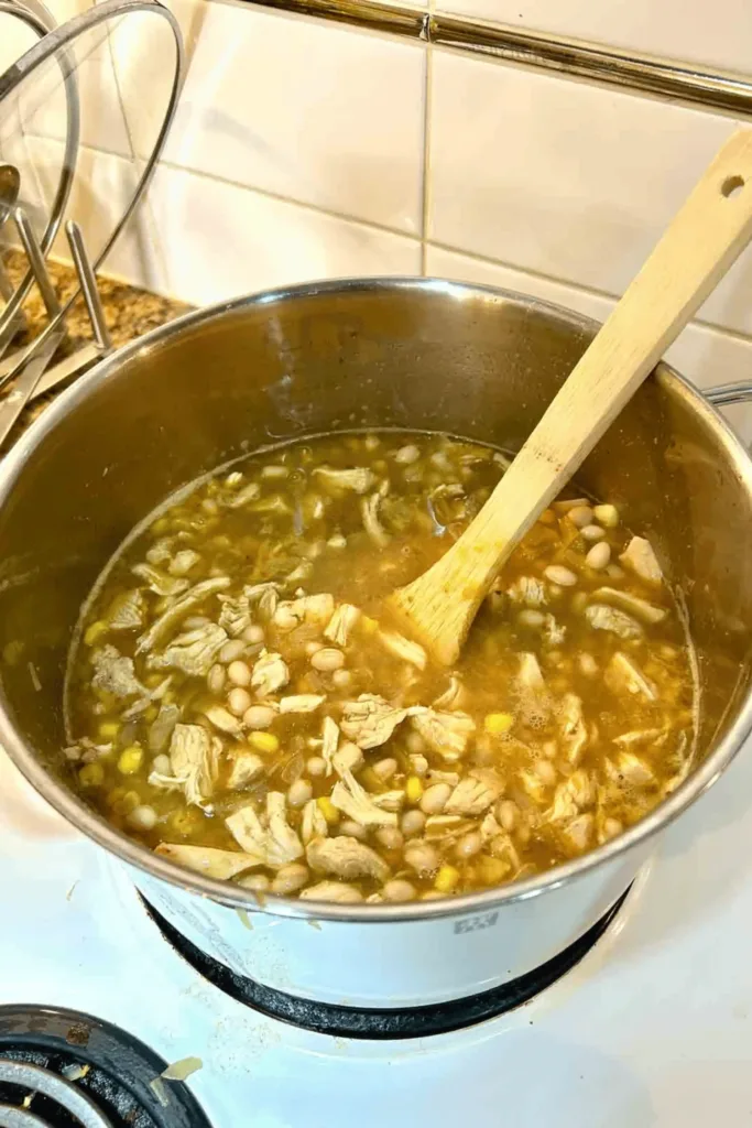 Add the chicken broth, beans, green chilis, chicken, corn, and seasonings