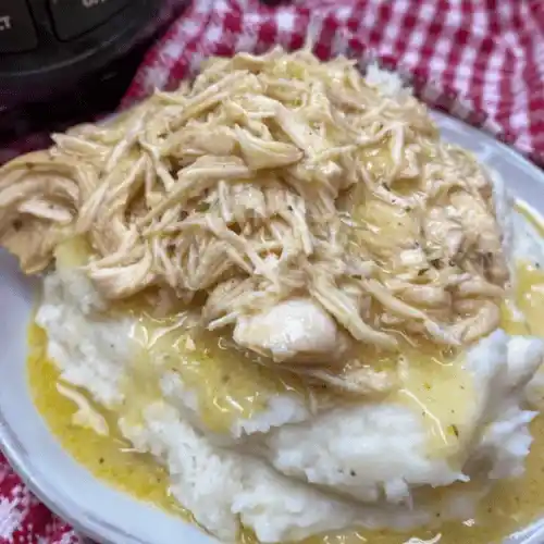 Ultimate Slow Cooker Chicken and Gravy served over mashed potatoes with parsley garnish
