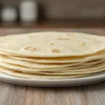 Homemade easy flour tortillas displayed on a wooden surface.