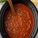 Crock Pot spaghetti sauce simmering in a slow cooker with fresh ingredients.