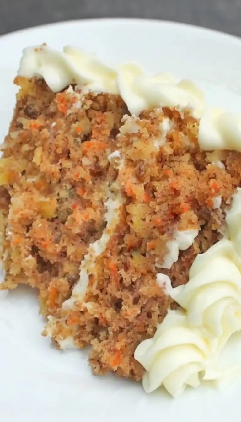 A slice of moist homemade carrot cake topped with cream cheese frosting